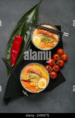 Schüsseln mit schmackhafter Thai-Suppe auf dunklem Hintergrund Stockfoto