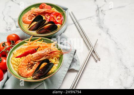 Schüsseln mit schmackhafter Thai-Suppe auf weißem Hintergrund Stockfoto