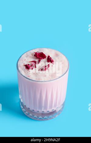 Ein Glas leckerer Rose Latte auf farbigem Hintergrund Stockfoto