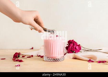 Frau, die auf dem Tisch Eis zum leckeren Rosenlatte im Glas gab Stockfoto
