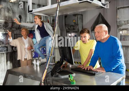 Großeltern und Enkelkinder, die sich im Fluchtzimmer mit einem Konundrommel herumtoben Stockfoto