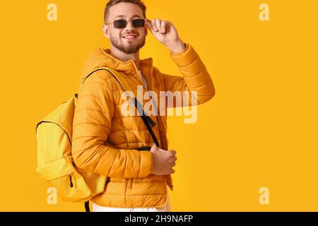Stilvoller junger Mann mit Sonnenbrille auf gelbem Hintergrund Stockfoto