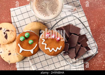 Lustige Kekse mit Schokolade und einer Tasse Kaffee auf farbigem Hintergrund Stockfoto