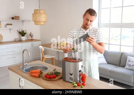 Junger Mann, der in der Küche gesunden Gemüsesaft zubereitet Stockfoto