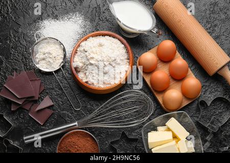 Frische Zutaten für die Zubereitung von Schokoladenteig auf schwarzem Hintergrund Stockfoto
