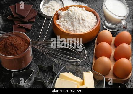 Frische Zutaten für die Zubereitung von Schokoladenteig auf schwarzem Hintergrund Stockfoto