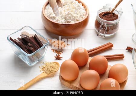Frische Zutaten für die Zubereitung von Schokoladenteig auf weißem Holzhintergrund Stockfoto
