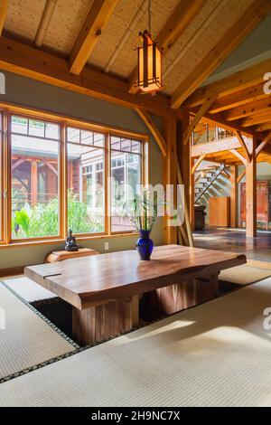 Lackierter Esstisch aus rustikalem Holz mit Tatami-Matten und einem kleinen indonesischen Teakholztisch im japanischen Esszimmer im Holzrahmen Stockfoto
