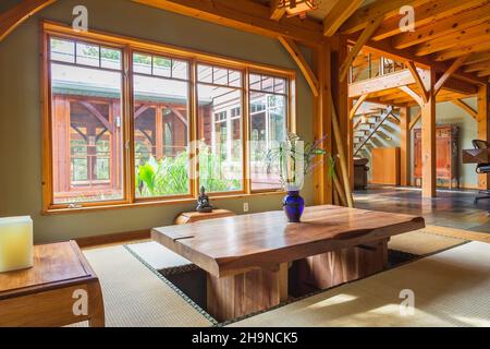 Lackierter Esstisch aus rustikalem Holz mit Tatami-Matten und kleinen indonesischen Teakholztischen im japanischen Speisesaal im Holzrahmen Stockfoto