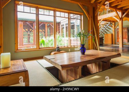 Lackierter Esstisch aus rustikalem Holz mit Tatami-Matten und kleinen indonesischen Teakholztischen im japanischen Speisesaal im Holzrahmen Stockfoto