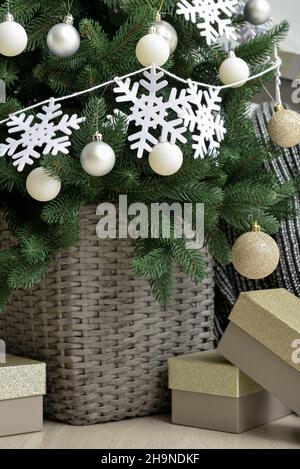 Schöner Weihnachtsbaum im Korb mit Schneeflocken, Kugeln und Geschenkboxen, Nahaufnahme dekoriert Stockfoto