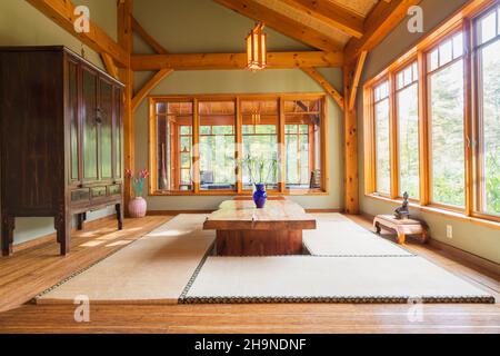 Lackierter Esstisch aus rustikalem Holz mit Tatami-Matten, schwarzem und braunem chinesischen Schrank, kleinen indonesischen Teakholztischen im japanischen Stil Stockfoto