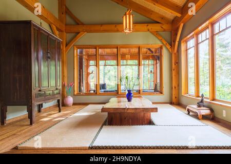 Lackierter Esstisch aus rustikalem Holz mit Tatami-Matten, schwarzem und braunem chinesischen Schrank, kleinen indonesischen Teakholztischen im japanischen Stil Stockfoto