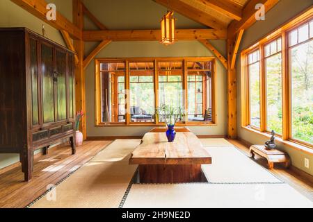 Lackierter Esstisch aus rustikalem Holz mit Tatami-Matten, schwarzem und braunem chinesischen Schrank, kleinen indonesischen Teakholztischen im japanischen Stil Stockfoto