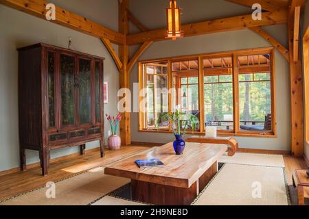 Lackierter Esstisch aus rustikalem Holz mit Tatami-Matten, schwarzem und braunem chinesischen Schrank im japanischen Speisesaal im Holzrahmen. Stockfoto
