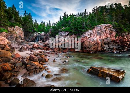 Wasserfall mit langer Belichtung trifft auf einen felsigen Strand Stockfoto