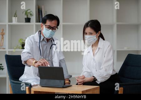 Leitender Arzt mit Sicherheitsschutzmaske unterstützt und jubelt jungen Patienten während des Hausbesuches während des Virus- und Krankheitsschutzes zu Hause an Stockfoto