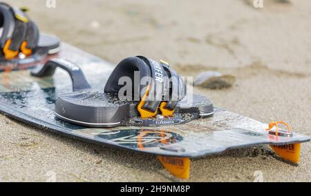 Kitesurfer bereitet seine Ausrüstung am Strand vor. Nahaufnahme Surfbrett auf dem Sand Stockfoto