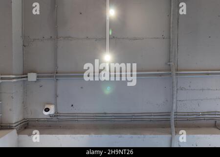 Abstraktes Loft-Interieur mit betongrauer Decke mit Belüftung und Überwachungskamera. Innenarchitektur und Deckengestaltung von Industrieloft Stockfoto