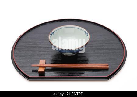 Reisschüssel mit Essstäbchen auf Tablett, traditionelles Geschirr aus Japan. Isoliert auf weißem Hintergrund. Stockfoto