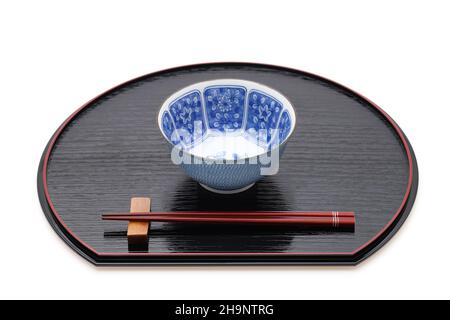 Reisschüssel mit Essstäbchen auf Tablett, traditionelles Geschirr aus Japan. Isoliert auf weißem Hintergrund. Stockfoto