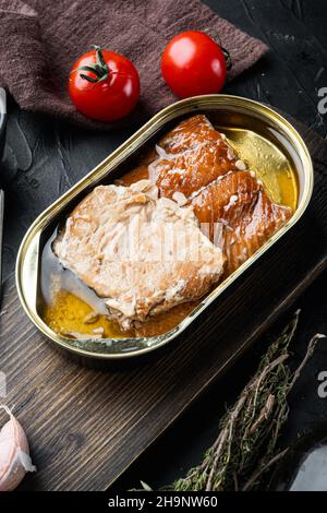 Geräucherter Lachsfilet Fischkonserven-Set, auf Holzschneidebrett, auf schwarzem Hintergrund mit Kräutern und Zutaten Stockfoto