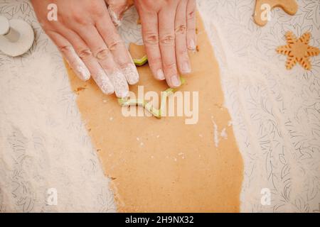 Frau Hände Formen Formen Kutter Ingwerteig und macht leckere weihnachten Ingwerkekse. Kochen und Dekorieren weihnachtsdessert. Stockfoto