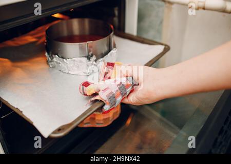Der Konditor bereitet köstliche rote Samtkuchen zu. Kochen in Backform. Stockfoto