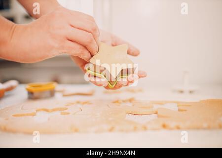 Frau Hände Formen Formen Kutter Ingwerteig und macht leckere weihnachten Ingwerkekse. Kochen und Dekorieren weihnachtsdessert. Stockfoto