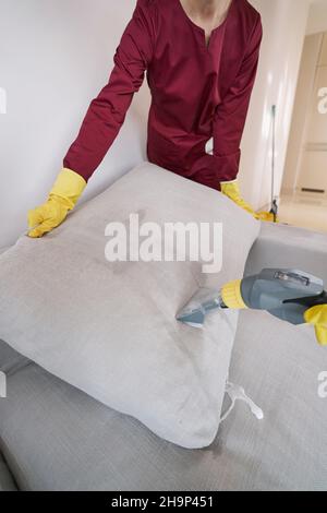 Hausmeister in Gummihandschuhen Dampf reinigende Sofakissen Stockfoto