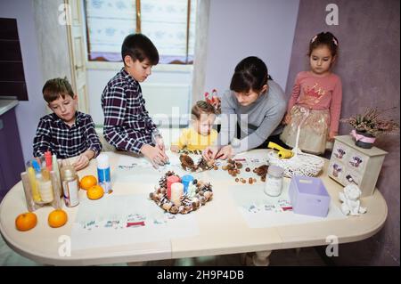 Mutter mit vier Kindern macht einen Kranz für Heiligabend und bastelt Dekoration. Neujahrsfest. Stockfoto