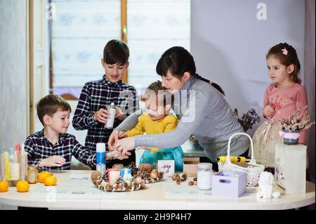 Mutter mit vier Kindern macht einen Kranz für Heiligabend und bastelt Dekoration. Neujahrsfest. Stockfoto