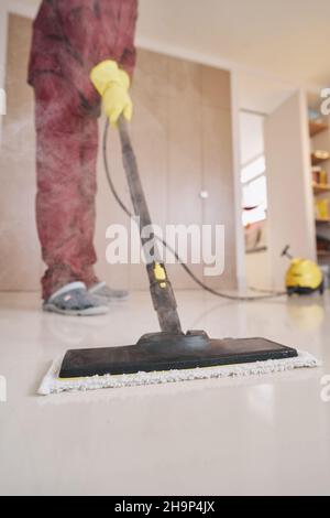 Hausmeister in Gummihandschuhen mit Dampfreinigungsgeräten Stockfoto