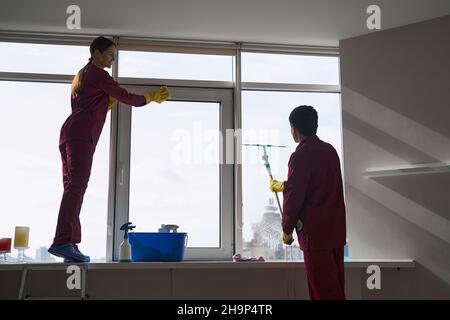 Das Reinigungspersonal verwendet Mikrofasertuch und Rakel zum Waschen der Fenster Stockfoto