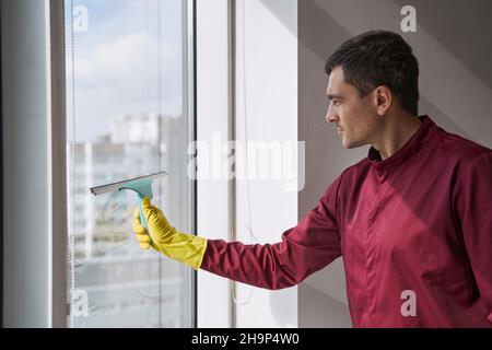 Housecleaner Reinigung der Glasoberfläche mit einem Werkzeug mit Gummiklinge Stockfoto