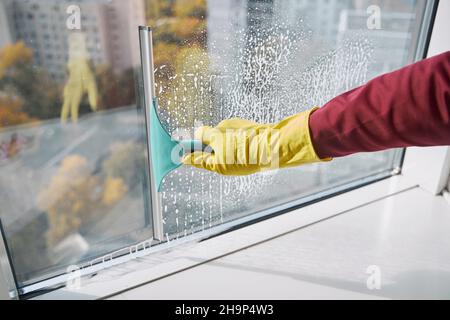 Fensterputzer zum Waschen der Fensterscheibe mit Arbeitsgerät und Gummiklinge Stockfoto