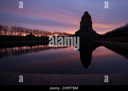 Leipzig, Deutschland. 08th Dez 2021. Die aufgehende Sonne färbt den Himmel hinter dem Monument der Völkerschlacht. Mit 91 Metern Höhe ist das imposante Bauwerk eines der größten Denkmäler Europas. Quelle: Jan Woitas/dpa-Zentralbild/ZB/dpa/Alamy Live News Stockfoto