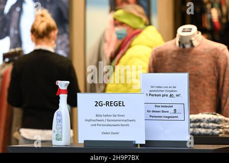 Mainz, Deutschland. 07th Dez 2021. Am Eingang des Modehauses Engbers in der Mainzer Innenstadt steht ein Schild mit der Aufschrift „2G Regel“. Bitte halten Sie Ihren Impfnachweis/Ihre Genetik und Ihren Ausweis bereit. Vielen Dank!“. Die Stadt Mainz hat ihre Corona-Verordnung geändert. Demnach dürfen Menschen mit einem 2G-Armband vom Weihnachtsmarkt auch in Mainzer Geschäften einkaufen gehen. (To dpa: 'Weihnachtseinkäufe mit Impfnachweise lassen die Registrierkassen seltener klingeln') Quelle: Arne Dedert/dpa/Alamy Live News Stockfoto