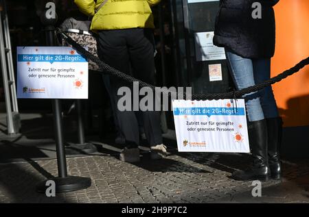 Mainz, Deutschland. 07th Dez 2021. Vor einem Laden für Handwerksbedarf in der Innenstadt von Mainz, Schilder mit der Aufschrift 'die Regel von 2G gilt hier. Aufnahme nur geimpfte oder wiedergeborene Personen an einem Cordon. Die Stadt Mainz hat ihre Corona-Verordnung geändert. Demnach dürfen Menschen mit einem 2G-Armband vom Weihnachtsmarkt auch in Mainzer Geschäften einkaufen gehen. (To dpa: 'Weihnachtseinkäufe mit Impfnachweise lassen die Registrierkassen seltener klingeln') Quelle: Arne Dedert/dpa/Alamy Live News Stockfoto