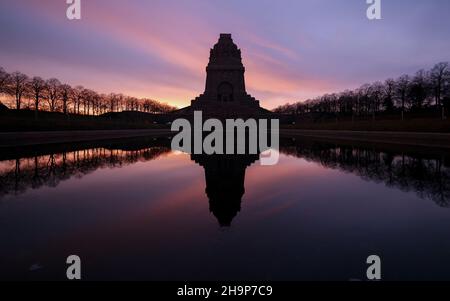 Leipzig, Deutschland. 08th Dez 2021. Die aufgehende Sonne färbt den Himmel hinter dem Monument der Völkerschlacht. Mit 91 Metern Höhe ist das imposante Bauwerk eines der größten Denkmäler Europas. Quelle: Jan Woitas/dpa-Zentralbild/ZB/dpa/Alamy Live News Stockfoto