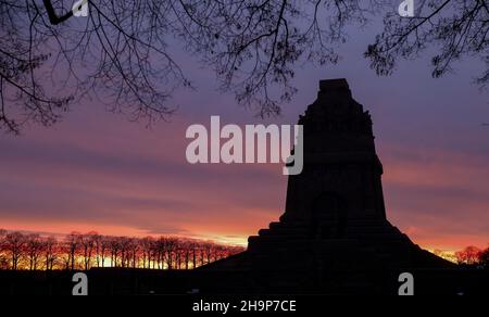 Leipzig, Deutschland. 08th Dez 2021. Die aufgehende Sonne färbt den Himmel hinter dem Monument der Völkerschlacht. Mit 91 Metern Höhe ist das imposante Bauwerk eines der größten Denkmäler Europas. Quelle: Jan Woitas/dpa-Zentralbild/ZB/dpa/Alamy Live News Stockfoto