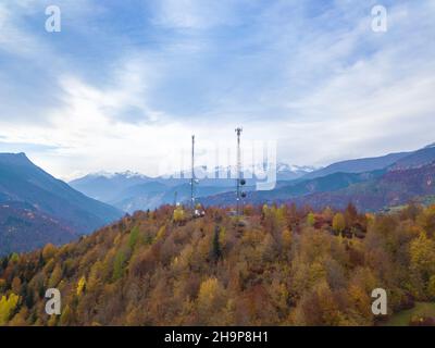 Drohnenansicht von zwei Hochspannungstürmen mit Antennen im Wald in den Bergen an einem Herbsttag. Stockfoto