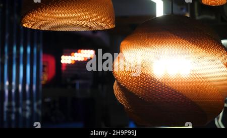 Warme Beleuchtung, die aus schönen Lampen kommt, während man eine heiße Tasse Kaffee in einem trendigen Café mit schöner Umgebung trinkt. Stockfoto