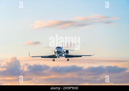 Privatjet auf dem Hintergrund eines schönen sanften Himmels mit Wolken bei Sonnenuntergang in rosa und blauen Tönen Stockfoto