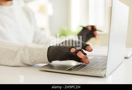 Mann in Druckhandschuhen Typ auf Laptop Stockfoto