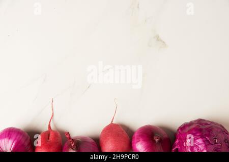 Gemüsekonzept auf dem sauberen weißen Kacheltisch werden ein paar violette Gemüsesorten in einer Linie sortiert. Stockfoto