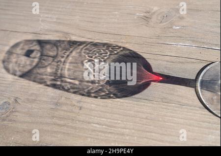 Schatten von einem Glas Rotwein auf einem Holztisch Stockfoto