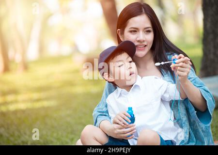 Asiatisch jung teen schön Mutter spielend mit sie Kind im Park draußen Stockfoto