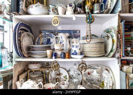 Regal mit einer Auswahl an Geschirr, Geschirr und Porzellan in einem Antiquitätengeschäft (Hampton Court Emporium, East Molesey, UK) Stockfoto