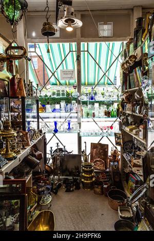 Ausstellung von Glaswaren, Büchern, Geschirr und Kupferwaren in einem Antiquitätengeschäft (Hampton Court Emporium, East Molesey, UK) Stockfoto